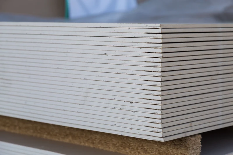 Close-up of stacked drywall panel edges showing the gypsum core and paper facing