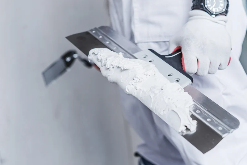 Taping knife loaded with joint compound held over a hawk