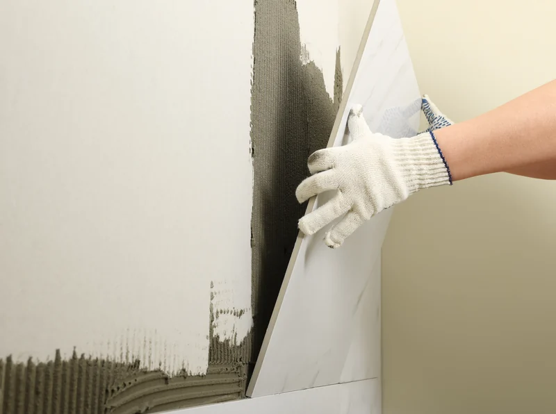 Board pressed onto daubs of adhesive on a wall