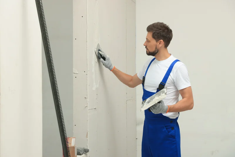 Worker skimming compound alongside a metal corner bead