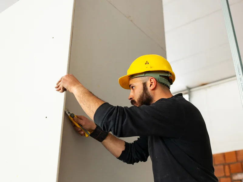 Measuring and marking a drywall panel during a project takeoff