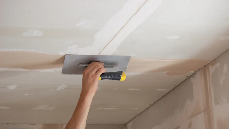 Trowel skimming compound across a ceiling